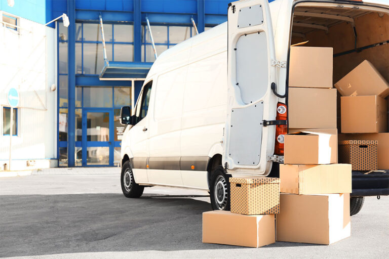 Camionnette de livraison ouverte chargée de cartons devant un entrepôt